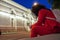 A plump woman with long curly dark hair in a red bright suit with a phone in her hands sits in the center of a European city on a