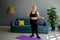 Plump woman training with yellow dumbbells in the living room