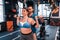 Plump woman working out with barbell near trainer