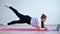 A plump young woman stands in a plank and watches an online fitness lesson on a laptop. Distance sports training.