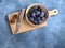 Plums in a bamboo bowl, a knife and a slit plum on a wooden board, a blue background