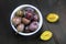 Plums in a bowl, whole and halved on dark brown wood