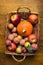 Plums Mirabelles red yellow green apples orange pumpkin in wicker basket on aged wood background. Thanksgiving autumn fall harvest