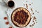 Plums pie with dried apricots on dark plate decorated with brown raisins and a cup of tea on light table with white cloth