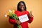 Plus size african american woman holding best mom message and tulips on mothers day happy with big smile doing ok sign, thumb up
