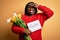 Plus size african american woman holding best mom message and tulips on mothers day stressed with hand on head, shocked with shame