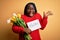 Plus size african american woman holding best mom message and tulips on mothers day very happy and excited, winner expression