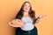 Plus size caucasian young woman holding bread celebrating achievement with happy smile and winner expression with raised hand