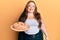 Plus size caucasian young woman holding bread looking positive and happy standing and smiling with a confident smile showing teeth