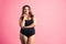 Plus size fashion model in black one-piece swimsuit, fat woman in lingerie on pink background