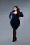 Plus size fashion model in blue dress, fat woman on gray studio background, overweight female body