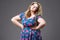 Plus size fashion model in floral dress, fat woman on gray background