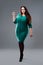 Plus size fashion model in green dress, fat woman on gray studio background, body positive concept