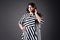 Plus size fashion model in striped dress, fat woman on gray background, overweight female body