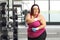 Plus size female exercising at a gym and holding painful shoulder