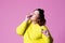 Plus size model eating macaroon, fat girl loves sweets, pink studio background