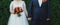 Plus size wedding couple is standing and hugging outside. Curvy bride is holding beautiful colorful bouquet with orange, red and