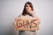 Plus size woman holding stop guns cardboard banner warning about violence cover mouth with hand shocked with shame for mistake,