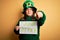 Plus size woman wearing green hat celebrating st patricks day holding saint patricks day banner pointing with finger to the camera