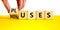Pluses and minuses symbol. Businessman turns a wooden cube and changes the word `minuses` to `pluses`. Beautiful yellow table,