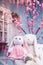 Plush Bunny sitting on white wooden bench at Blooming oriental cherry and blue background.