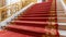 a plush red carpet cascades down the stairs, adorning the interior of a lavish hotel or restaurant, exuding elegance and