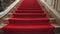 a plush red carpet cascades down the stairs, adorning the interior of a lavish hotel or restaurant, exuding elegance and