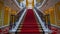 a plush red carpet cascades down the stairs, adorning the interior of a lavish hotel or restaurant, exuding elegance and