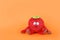 Plush red strawberry toy for little kids on bright orange background. Childhood concept. Copy space