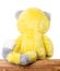 Plush yellow toy sitting on a wooden table, close-up rear view with copy space for text