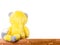 Plush yellow toy sitting on a wooden table, close-up rear view with copy space for text