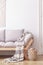 Plywood lantern next to a wooden sofa with gray cushions and a blanket in a simple living room interior