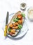 Po` boy sandwich with crispy cornmeal shrimp, tomatoes, cilantro and mayo herbs sauce on light background, top view