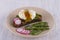 Poached egg on a piece of bread with fried green beans, radish and arugula on a plate