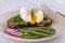 Poached egg on a piece of bread with fried green beans, radish and arugula on a plate