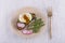 Poached egg on a piece of bread with fried green beans, radish and arugula on a plate