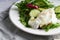 Poached eggs with herbs, avocado and cucumber served on a plate on a light background Closeup