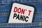 In a pocket of jeans there is a smartphone on the screen of which the text - DONT PANIC