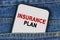 In a pocket of jeans there is a smartphone on the screen of which the text - INSURANCE PLAN