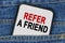 In a pocket of jeans there is a smartphone on the screen of which the text - REFER A FRIEND