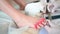 Podiatrist using grinding equipment and making procedure polish for feet pedicure. Podology beautician in white gloves cleaning