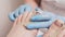 Podiatrists hands in blue medical gloves insert a silicone fixator to a client's foot with inrown nail. Closeup. The