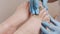 Podologists hands in blue medical gloves insert a silicone fixator to a client's foot with ingrown nail. Closeup