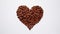 A poignant image of a large brown heart made from coffee beans, pierced by a brown arrow with red h