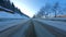Point of view: driving on country snow-covered track along the trees in the morning sunny time