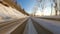 Point of view: driving on country snow-covered track along the trees in the morning sunny time