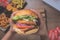 Point of view of a person eating a handmade burger, with several portions of fried snacks on the table