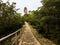 Point of view person walking in tree bush lined avenue on stone rock pathway Concept of exploration, travel and freedom outdoors