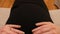 Point of view of pregnant woman stroking her tummy while sitting on the sofa