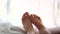 Point of view shot of woman\'s feet lying on bed with the summer sun shining into the room.